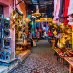 Bunter Markt in einer engen Gasse mit traditionellen marokkanischen Waren und Laternen