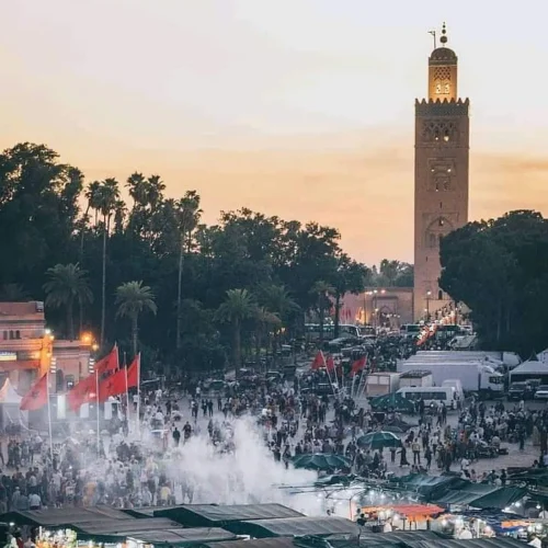 Abendstimmung auf dem belebten Djemaa el Fna Platz in Marrakesch mit Koutoubia-Moschee im Hintergrund
