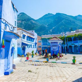 Blau gestrichene Häuser und gepflasterter Platz in der Altstadt von Chefchaouen mit Blick auf das Rif-Gebirge