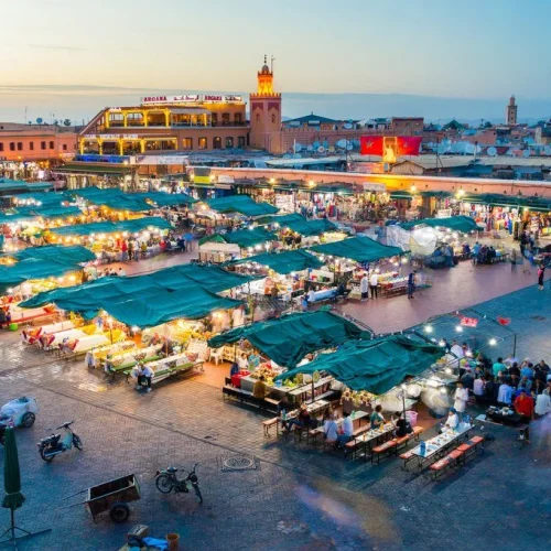 Abendliche Ansicht des Djemaa el Fna Platzes in Marrakesch mit beleuchteten Marktständen und Menschenmenge
