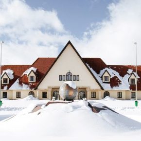 Verschneites Gebäude mit roten Dächern und Brunnen im Vordergrund im Wintersportort Ifrane im Atlasgebirge